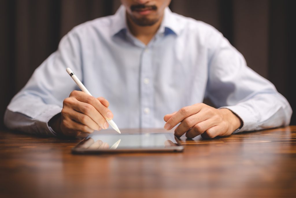 Dokunmatik kalem ile tablet üzerinde not alan iş insanı.